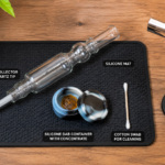 Nectar collector dab straw setup on wooden table with butane torch, silicone wax container, and cotton swab cleaning supplies — complete guide visual